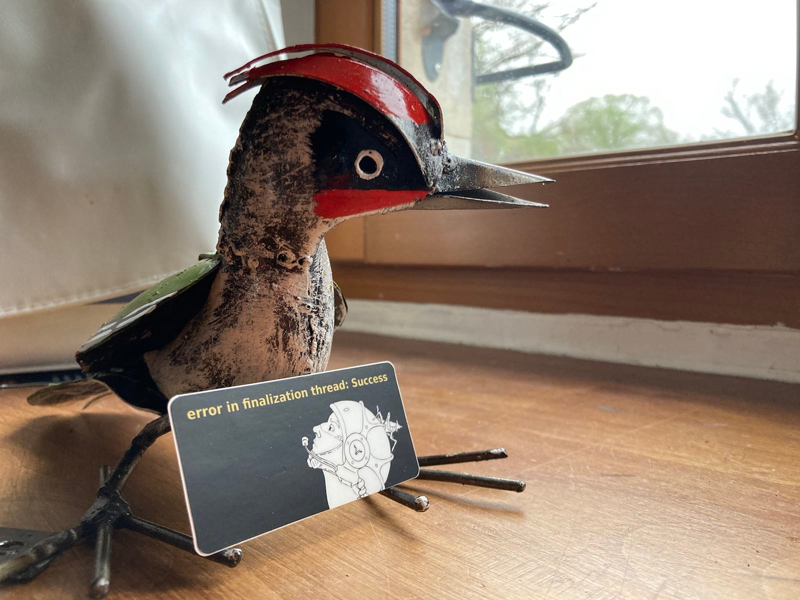 Picture of a metal bird holding an error/success sticker (under CC0).